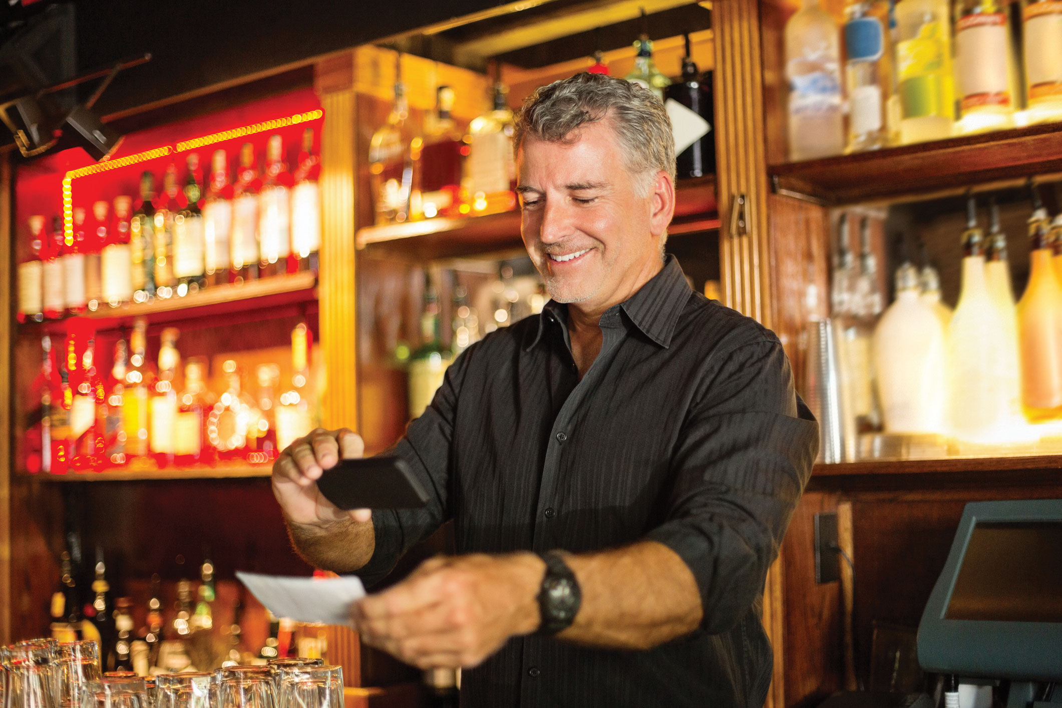 Bartender taking picture of check with phone for mobile check deposit