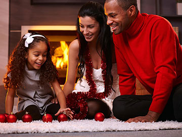 family in front of fireplace organizing Christmas ornaments.