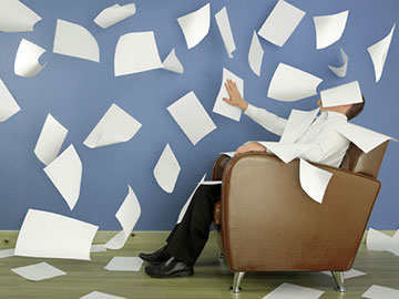 man in chair trying to organize papers flying everywhere!