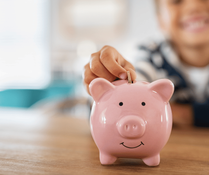 Kid putting money in piggy bank
