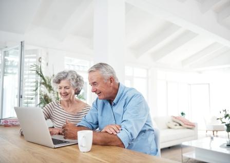 retired couple looking at their laptop in the living room