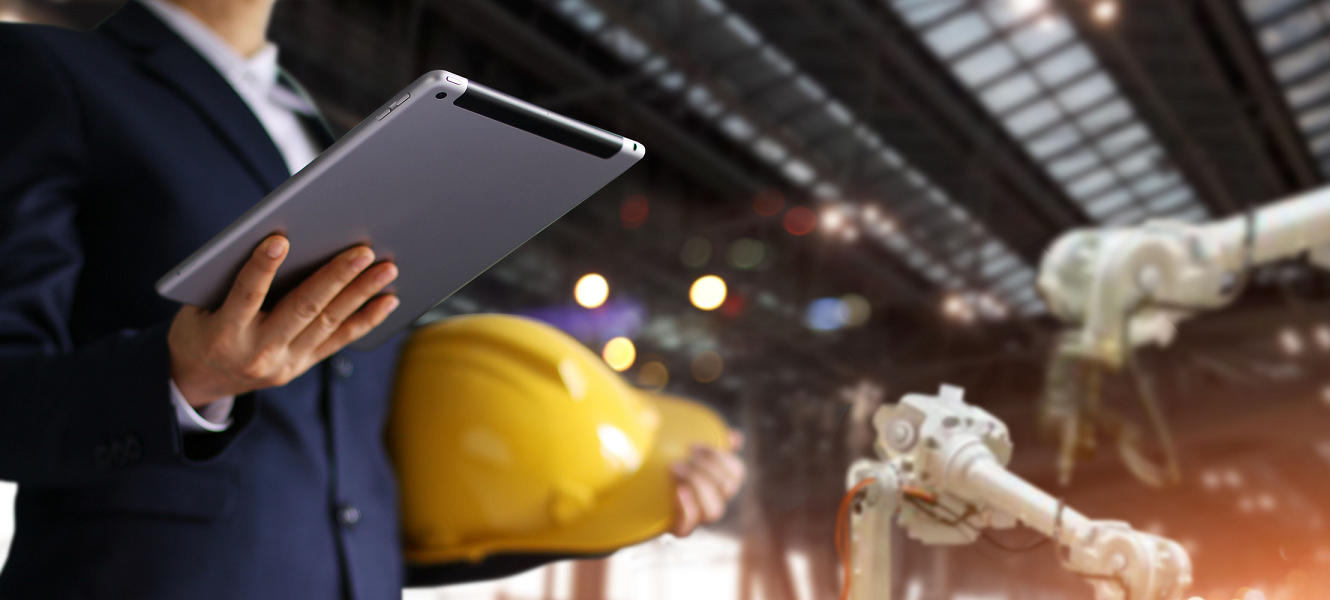 banker at manufacturing plant holding ipad and hardhat